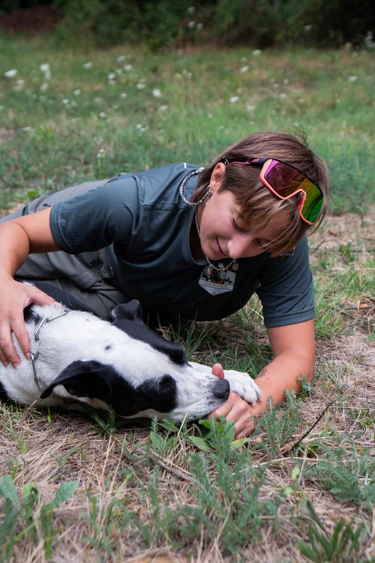 Anna sdraiata sull’erba che gioca con un cane bianco e nero