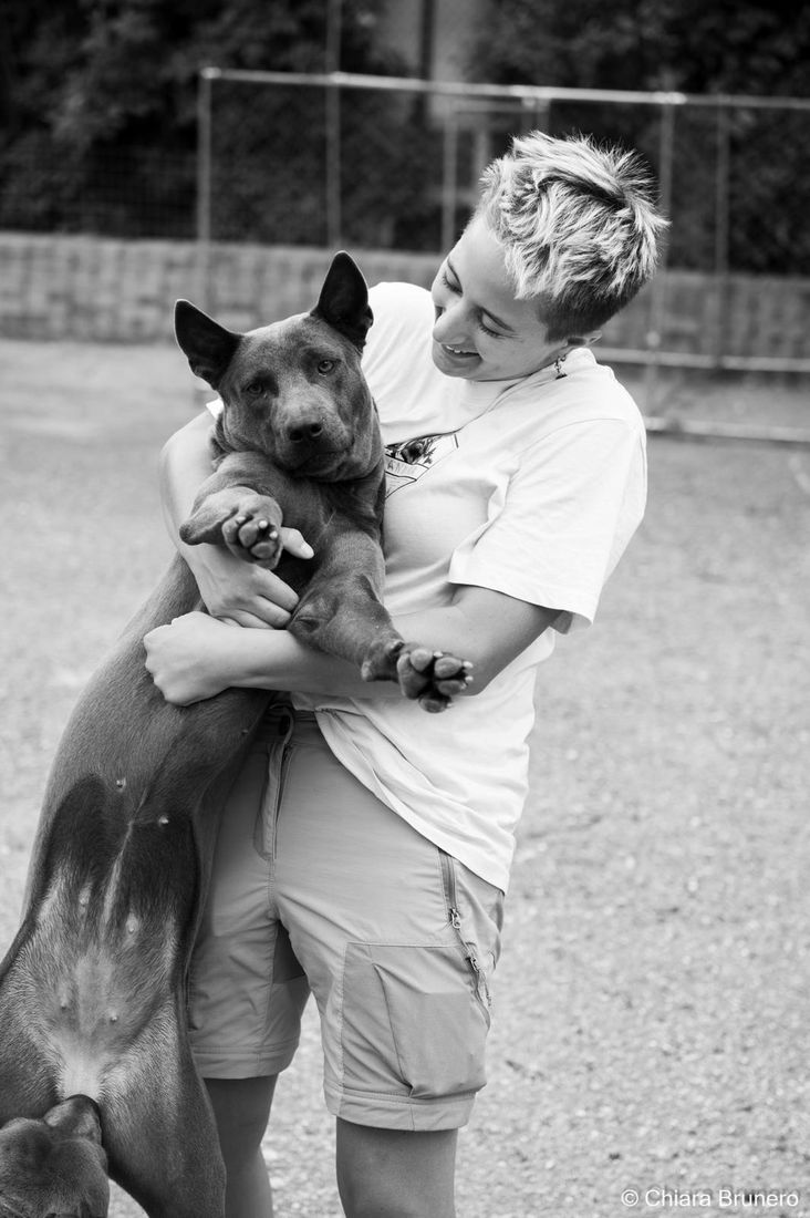 Anna sorride tenendo in braccio un Thai Ridgeback (foto in bianco e nero)
